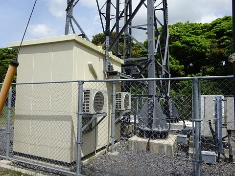 Equipment cabin, outdoor cooling units and cable runs at the base of the shared tower.