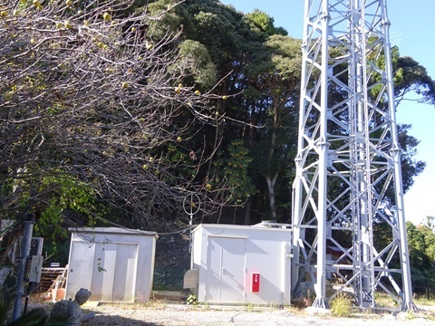 Two equipment cabins at the foot of the Johor-facing lattice tower, photographed on the November return visit.